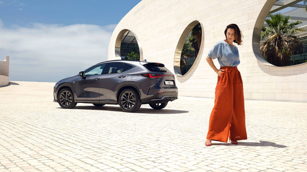 A person stood in the foreground of a parked Lexus NX